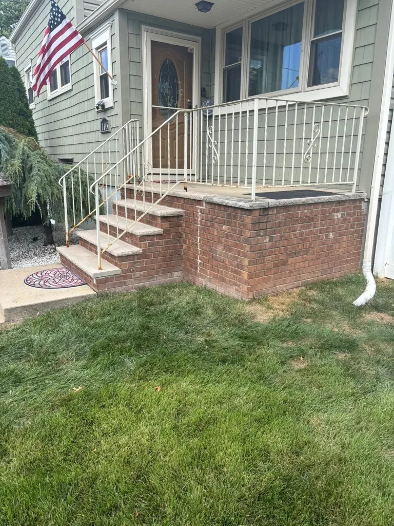 Brick front steps and porch with a metal railing