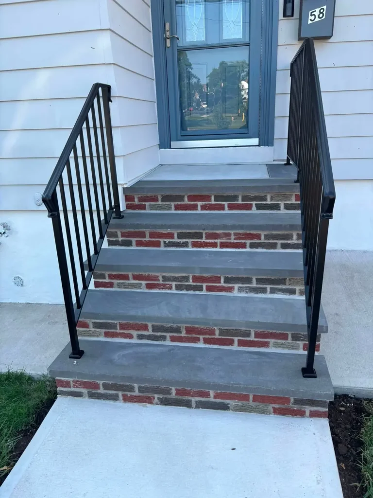 Brick front steps with stone treads and black iron railings