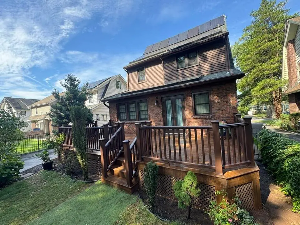 Finished deck with brown railings behind a brick house