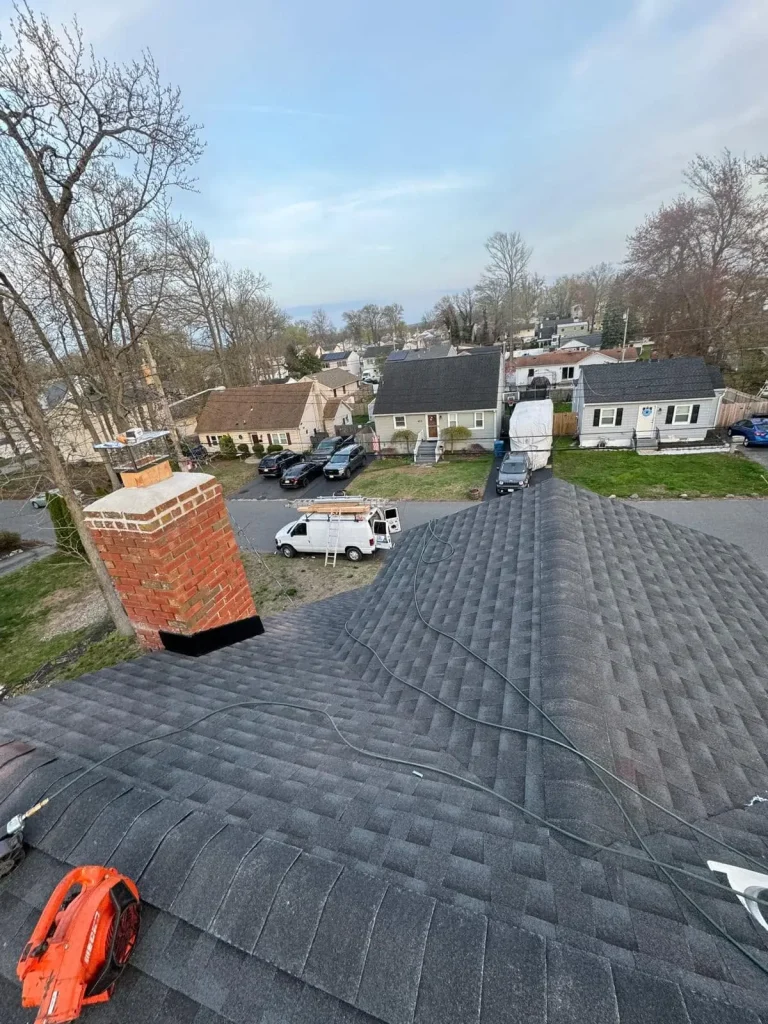 New charcoal architectural shingle roof around a brick chimney