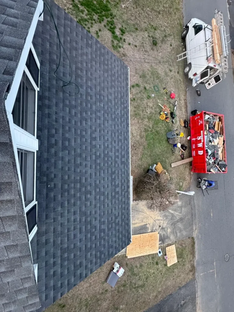 Newly shingled roof slope with the crew trailer parked in the driveway below