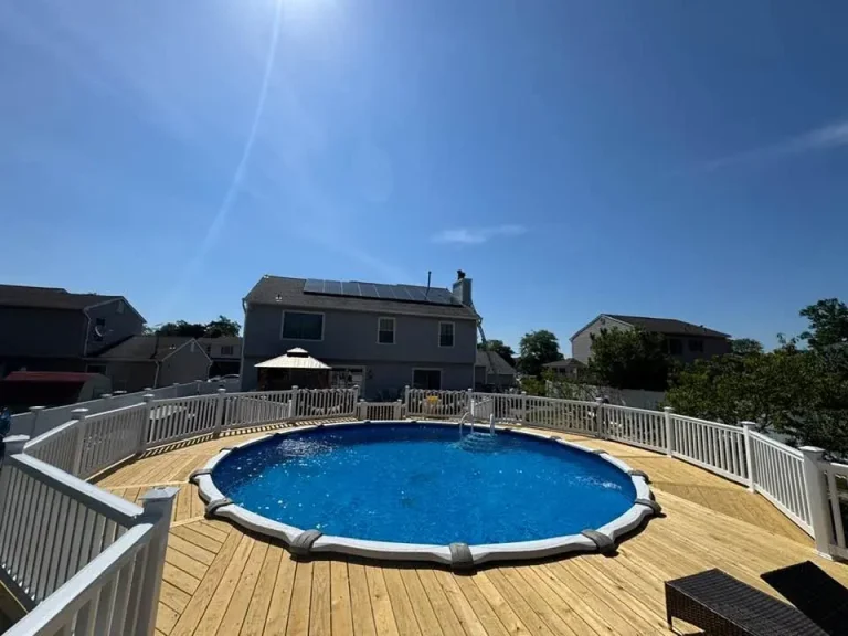 Finished pool deck with white railing around an above-ground pool