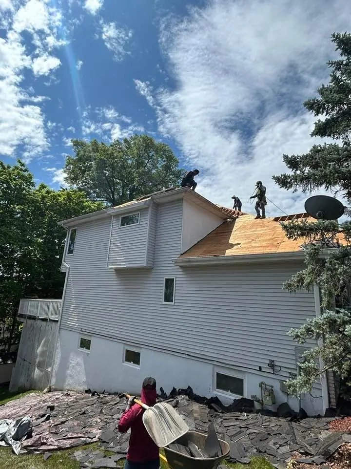 Roofers working on a new roof deck on a split-level home